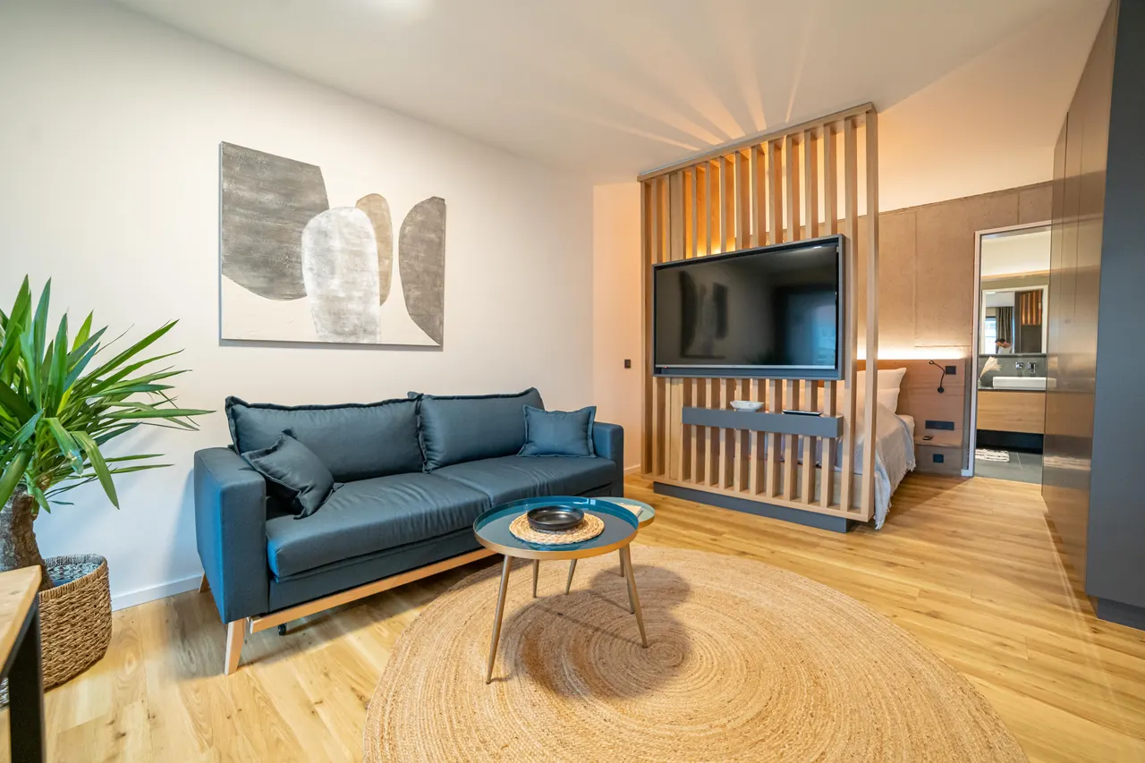 Wohnraum mit blauem Sofa und hölzernem Raumteiler